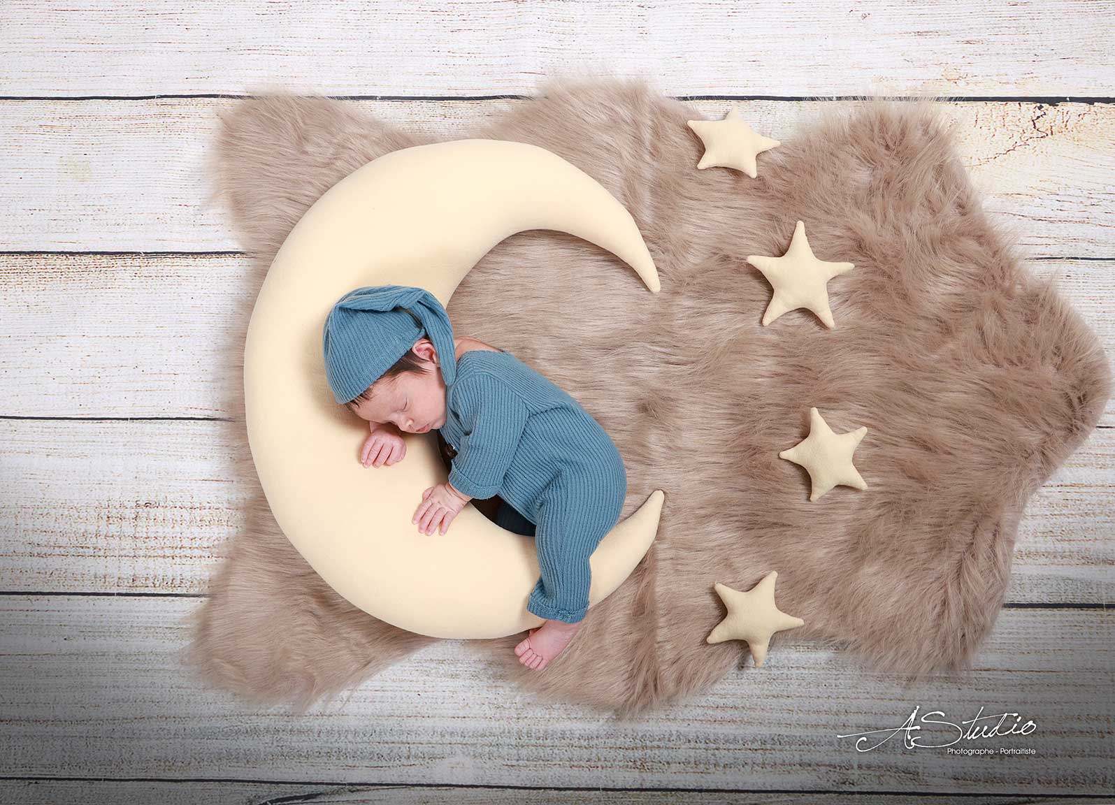 Nouveau-né endormi sur une lune, photographié au studio AStudio à Fougères
